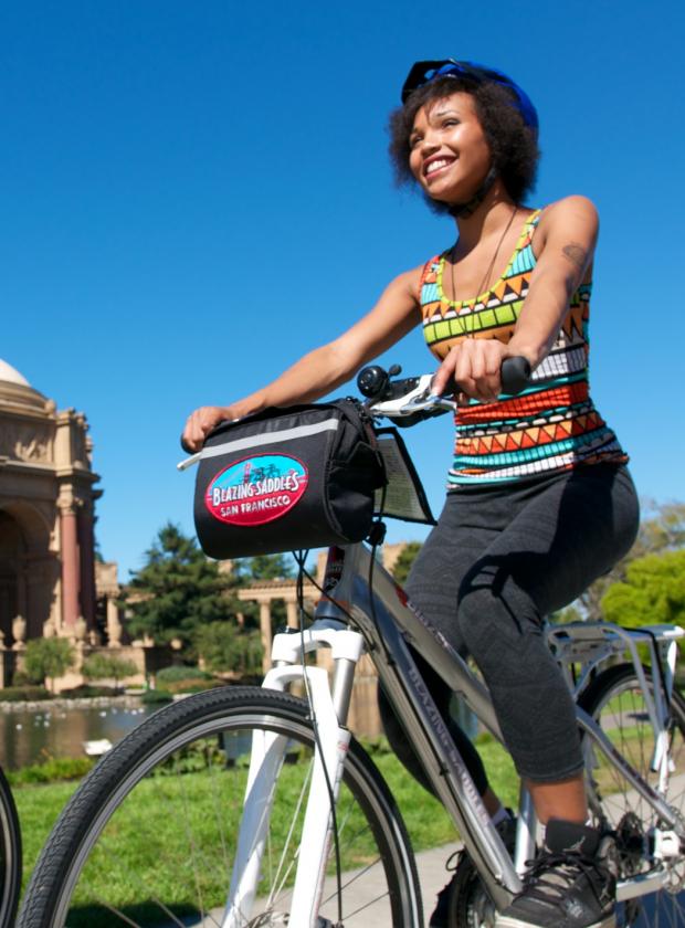 Couple smiling and biking in front of the Palace of Fine Arts